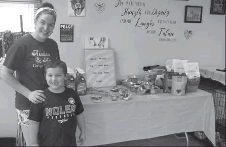 Audrey Lohrey and Beau Schumacher, 6, of Woodsfield, in front of a variety of dog supplies available to purchase for donation during the Dog Days of Summer fundraiser for the Monroe County Dog Pound, Saturday, Aug. 31 at Audies Angels Grooming Shop in Woo